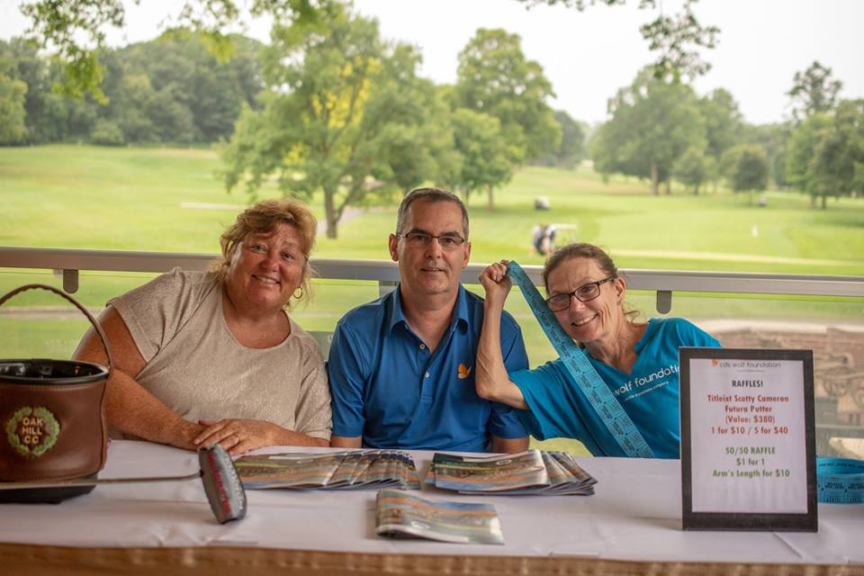 Group of three people sitting at the Teeing for abilities raffle table selling tickets and smiling