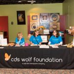 Three CDS employees sitting at an informational table ready to spread information about CDS