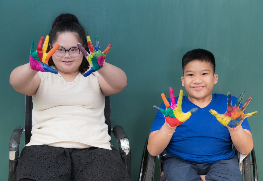 Group of special students in classroom, a down syndrome girl, two handicapped boys and cute Asian teacher playing toy and game together.